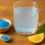 Glass mug of blue saltwater with Persian blue salt and lemon on a wooden table
