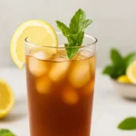 Long Island Iced Tea mocktail in a tall glass with lemon and mint