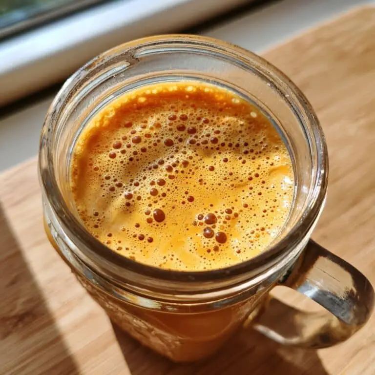 Frothing pumpkin cream cold foam in a glass jar with handheld frother