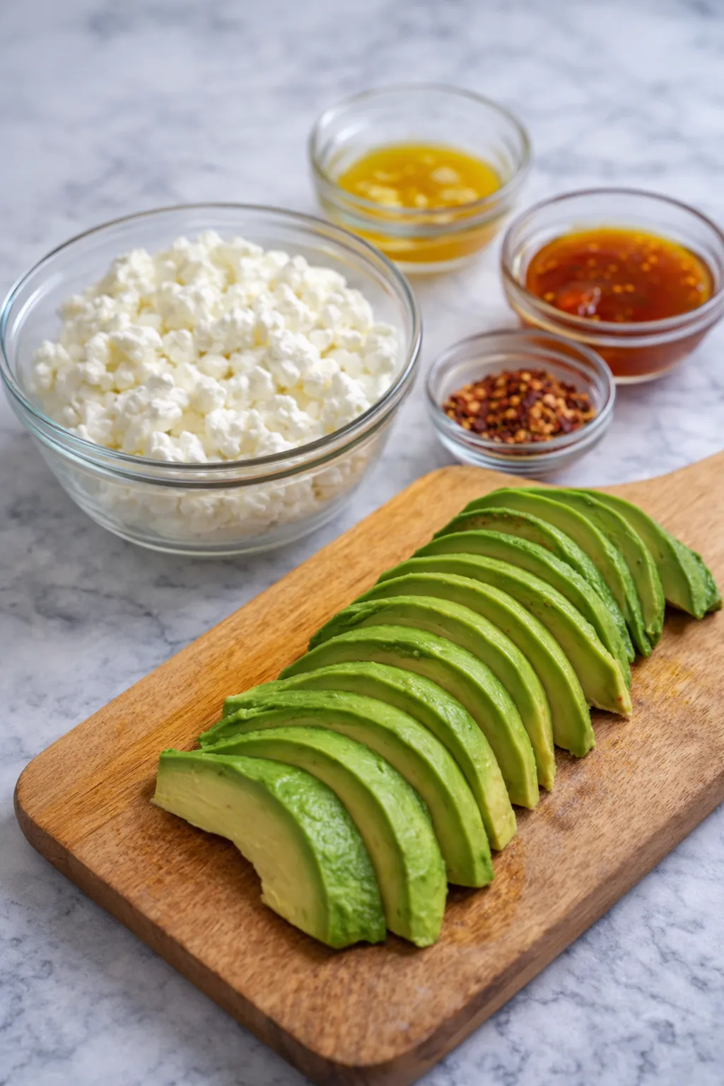 Cottage cheese, sliced avocado, and spicy hot honey drizzle prepared as creamy and flavorful toppings for a high protein power bowl.