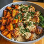 A close-up of a healthy Chicken and Sweet Potato Bowl with rice, roasted sweet potatoes, chicken pieces, and broccoli, drizzled with sauce and parsley.