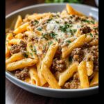 A close-up of a bowl filled with creamy beef pasta, topped with grated cheese and parsley.