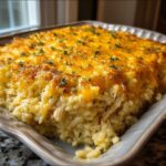 A close-up of a freshly baked Creamy Chicken Rice Casserole topped with melted cheddar cheese and parsley.