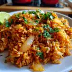 A close-up of a plate filled with flavorful Easy Mexican Rice Recipe, garnished with fresh cilantro and a lime wedge.