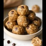 A bowl overflowing with Easy No Bake Lactation Energy Balls, studded with chocolate chips and oats.