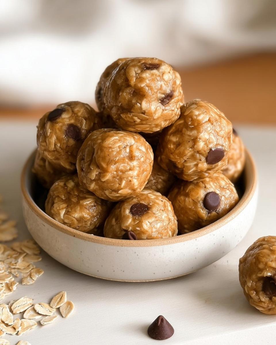 A bowl overflowing with Easy No Bake Lactation Energy Balls, studded with chocolate chips and oats.