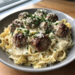 A bowl of Garlic Butter Meatballs with Parmesan Linguine, topped with fresh parsley and grated Parmesan cheese.