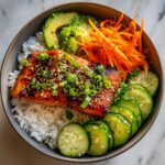 A close-up of a Honey Glazed Salmon Rice Bowl with perfectly cooked salmon, rice, avocado, cucumber, and shredded carrots.