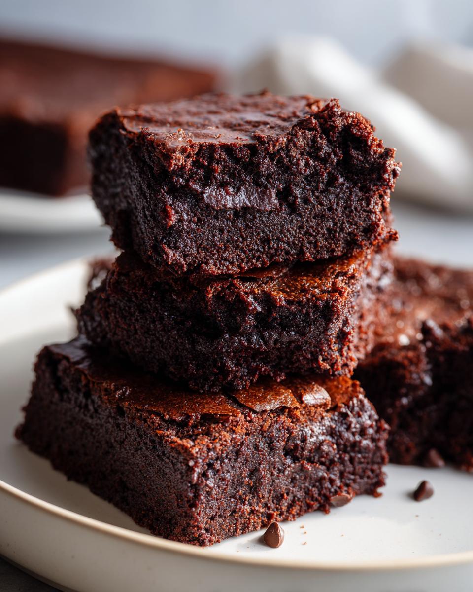 A stack of fudgy Keto Cottage Cheese Brownies, with a rich chocolatey texture and a slightly cracked top.