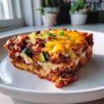 A slice of Keto Ground Beef Casserole with layers of ground beef, cheese, and zucchini on a white plate.