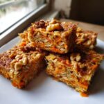 Close-up of No Sugar Cottage Cheese Carrot Cake Bars topped with walnuts, showcasing layers of shredded carrots and oats.