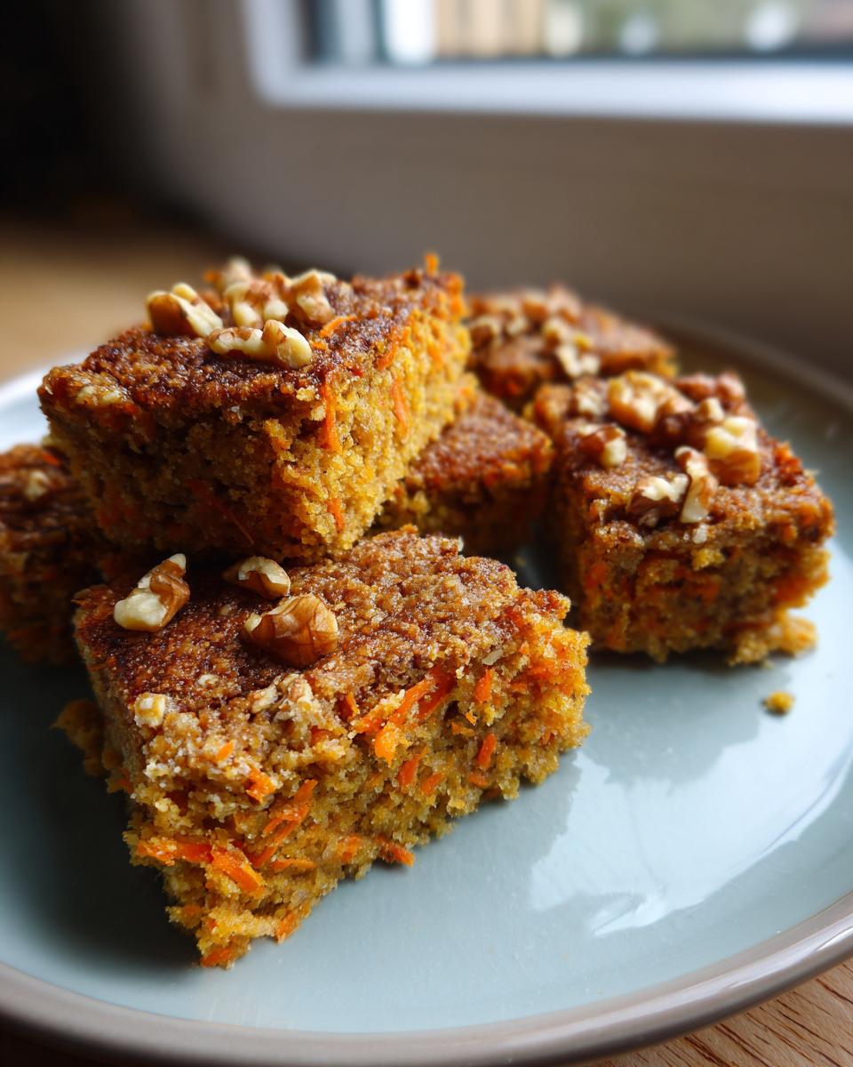 Close-up of No Sugar Cottage Cheese Carrot Cake Bars topped with walnuts on a light blue plate.