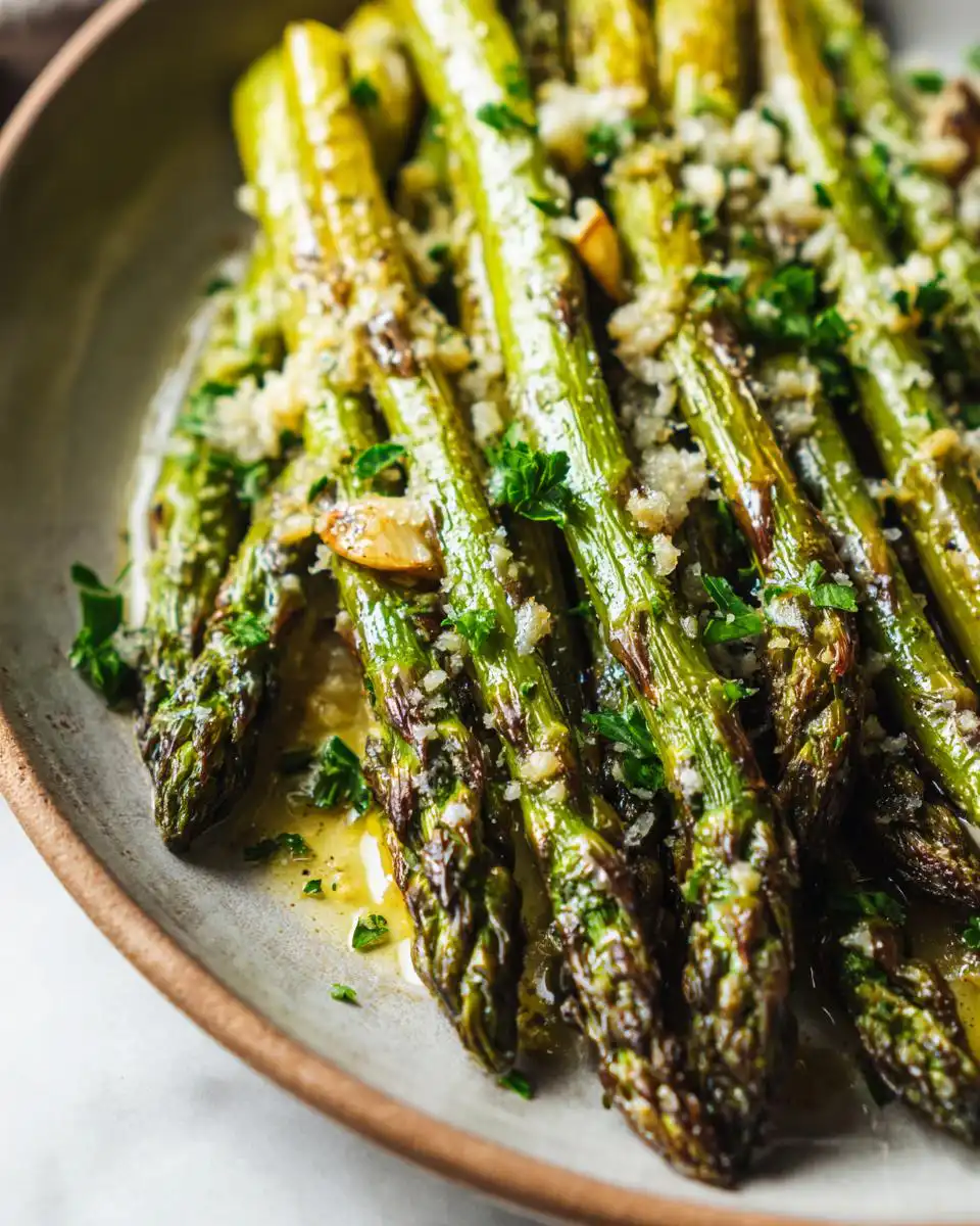 Close-up of tender Parmesan Roasted Asparagus drizzled with butter and sprinkled with fresh parsley and garlic.