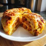 A slice of Sausage Stuffed Potato Loaf, showing layers of potatoes and savory sausage filling, topped with melted cheese.