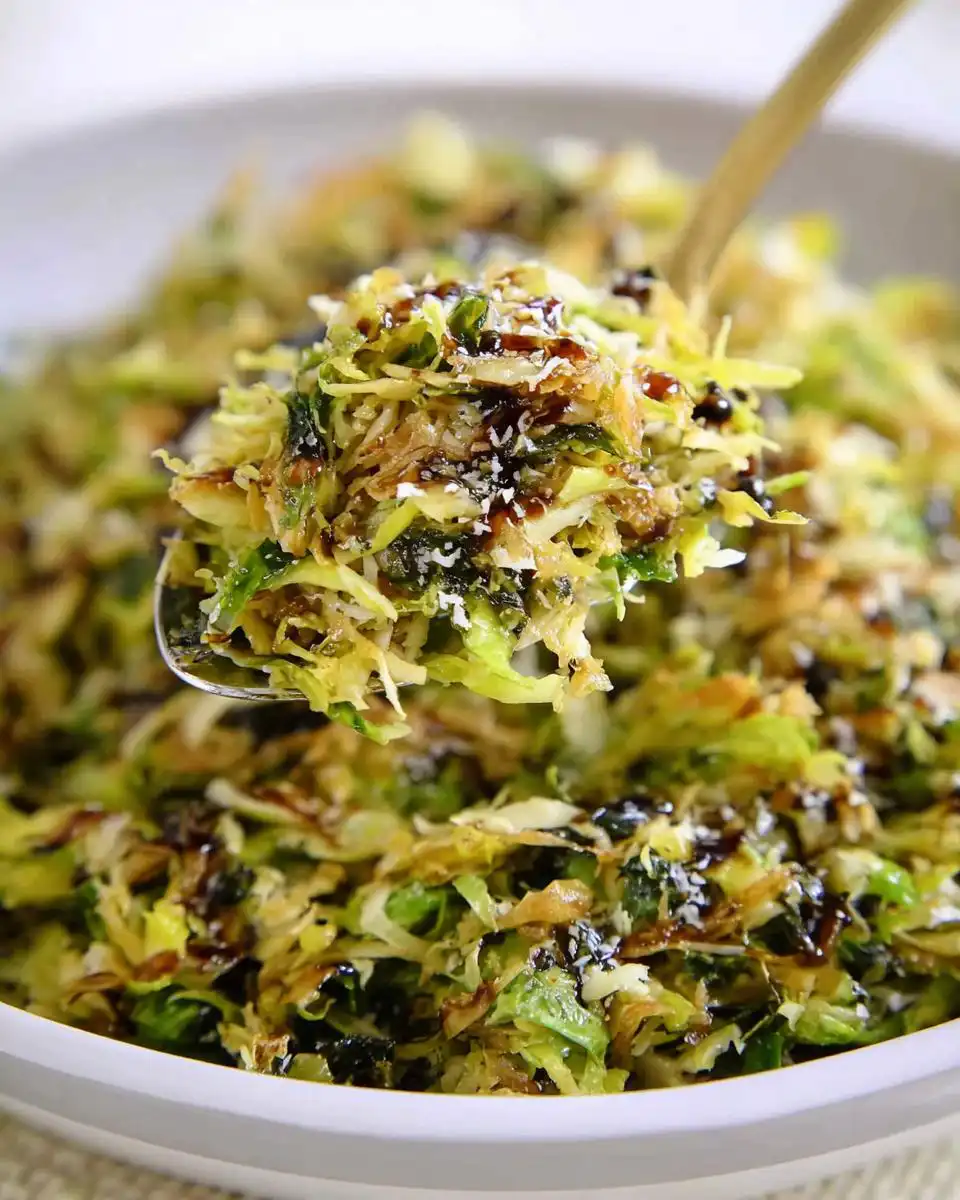 A spoonful of shredded brussels sprouts drizzled with balsamic glaze and topped with parmesan cheese.