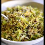 Close-up of a forkful of delicious shredded Brussels sprouts topped with grated Parmesan cheese.