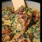 Close-up of tender chicken pieces in a creamy sauce with spinach and sun-dried tomatoes for slow cooker tuscan chicken.