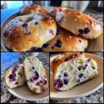 A plate of golden-brown sourdough blueberry bagels, some whole and one sliced in half to show the juicy blueberry interior.
