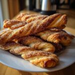 A pile of golden brown sourdough discard cinnamon sugar twists, glistening with sugar crystals.