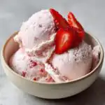 A bowl of creamy Strawberry Cottage Cheese Ice Cream topped with fresh strawberry slices.