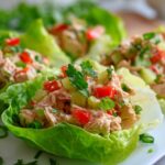Close-up of Easy Tuna Lettuce Wraps filled with tuna salad, tomatoes, cucumber, and green onions.