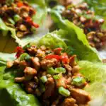 Close-up of healthy chicken lettuce wraps filled with savory chicken, cashews, red peppers, and green onions.