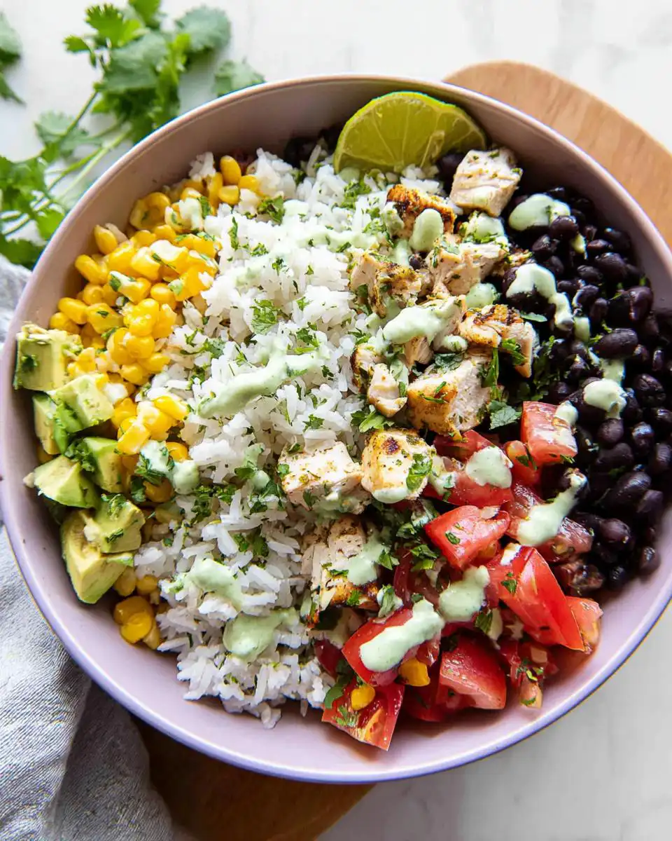 A vibrant High Protein Cilantro Lime Rice Bowl with chicken, avocado, black beans, corn, tomatoes, and lime.