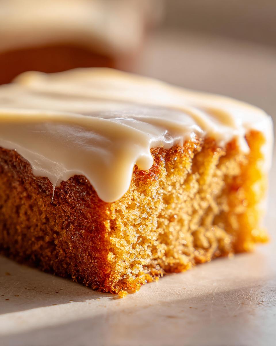 A close-up of a slice of Coffee Fudge Traybake, generously topped with creamy white icing.