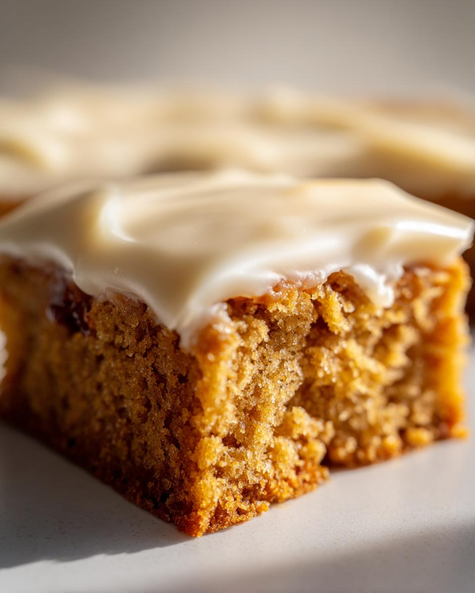 Close-up of a moist Coffee Fudge Traybake slice topped with smooth, creamy white icing.
