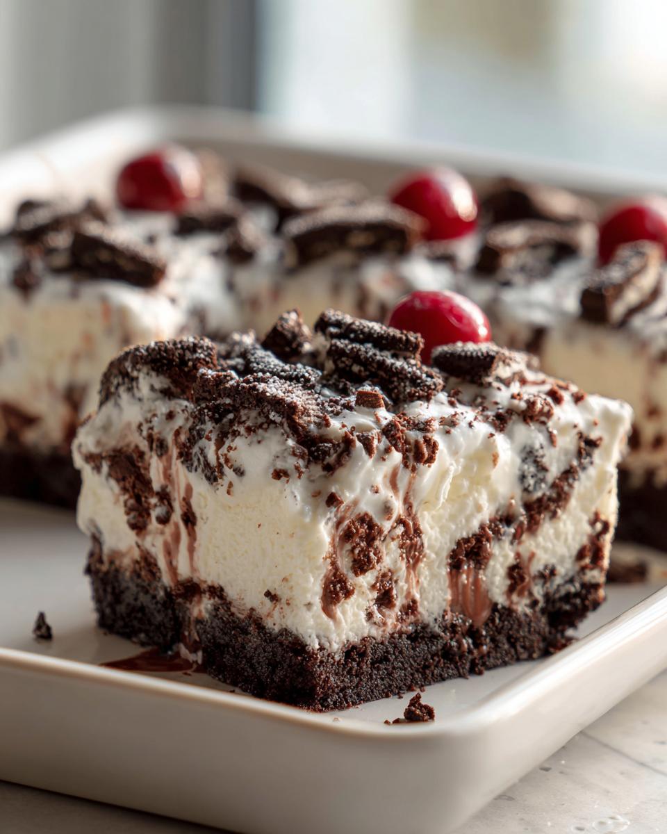 A tempting slice of easy Oreo dessert bars, featuring a rich chocolate base, creamy filling, crushed Oreos, and topped with cherries.