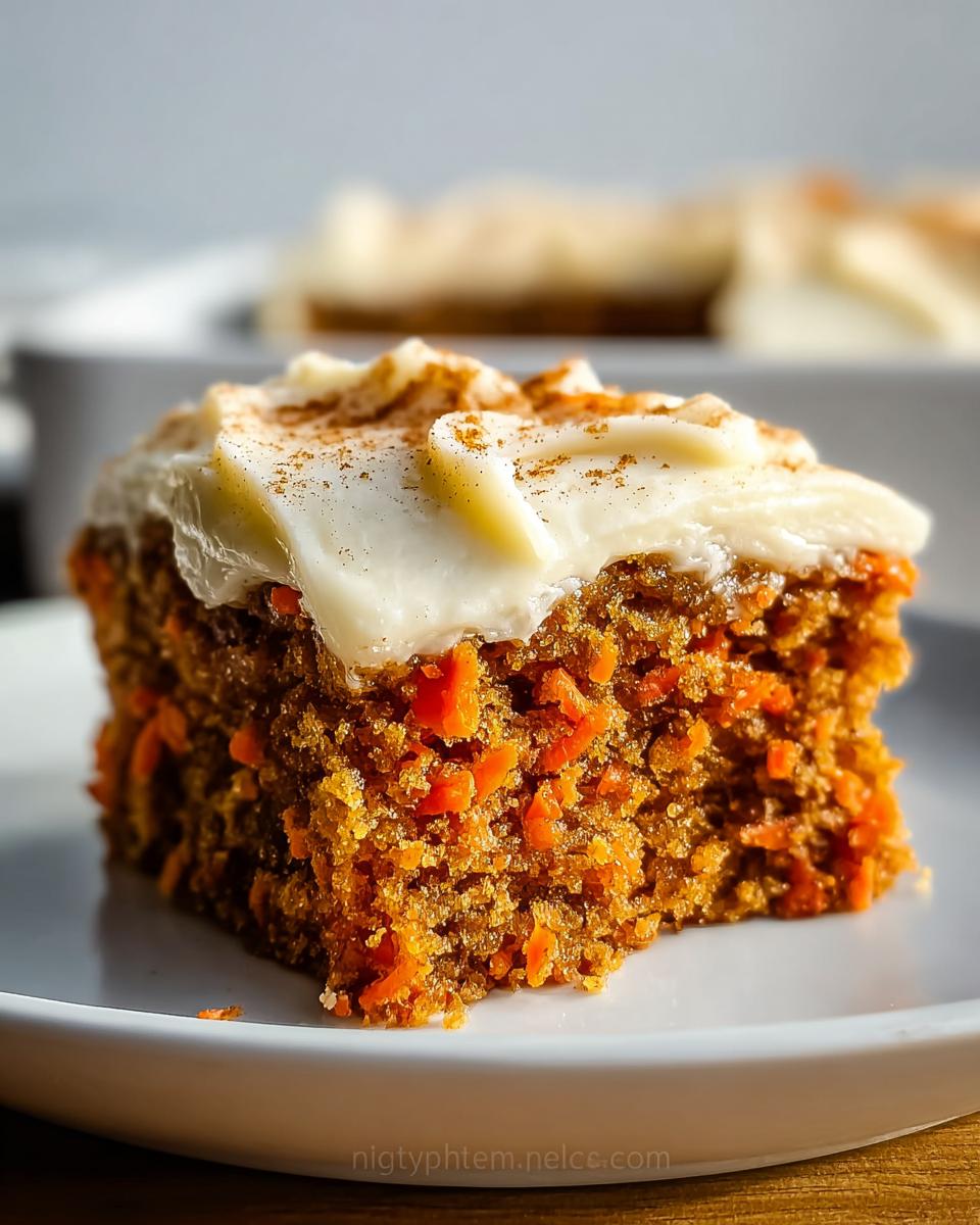 A slice of delicious Gluten Free Carrot Cake topped with cream cheese frosting and a sprinkle of cinnamon.