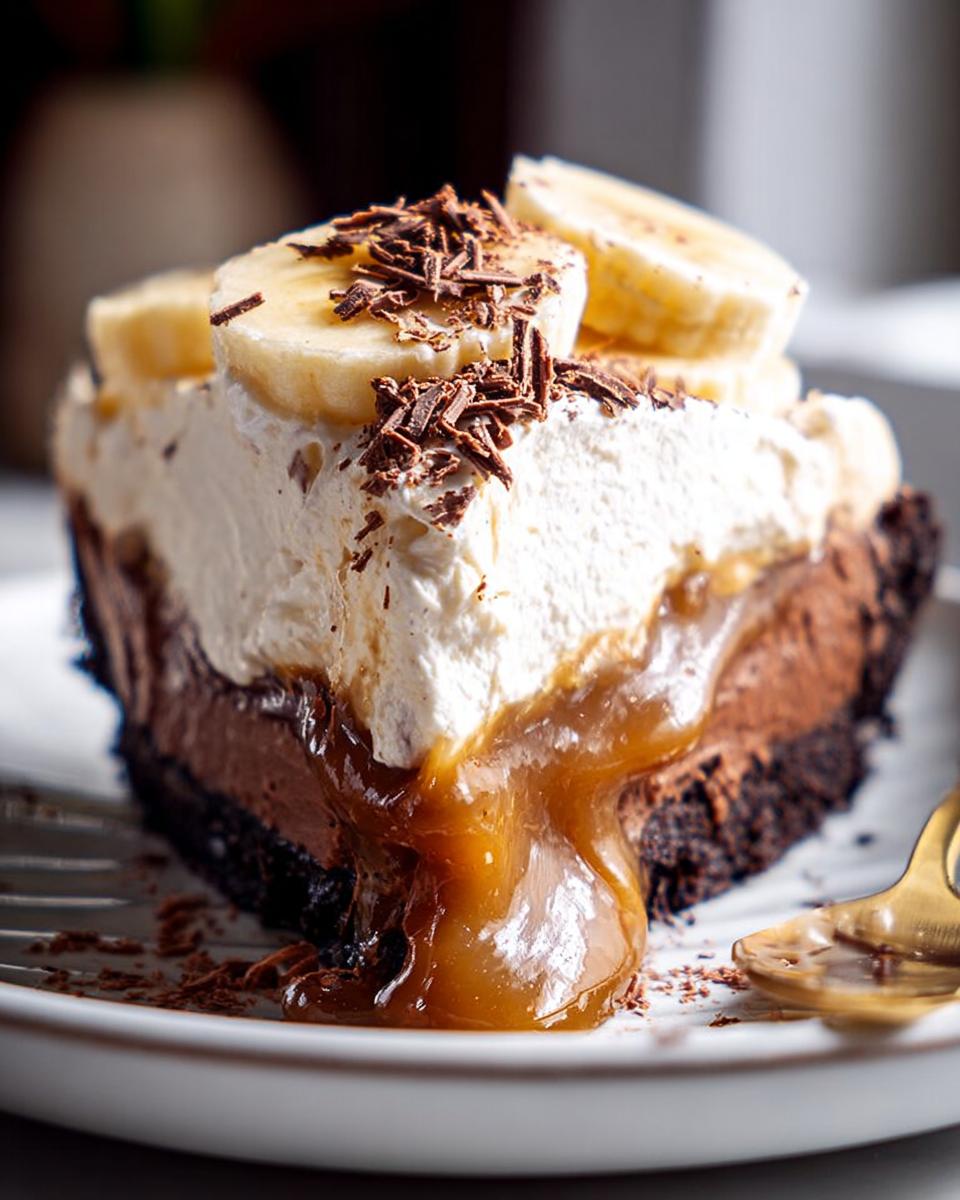 A decadent slice of Mary Berry inspired Chocolate Banoffee Pie, topped with whipped cream, banana slices, and chocolate shavings.