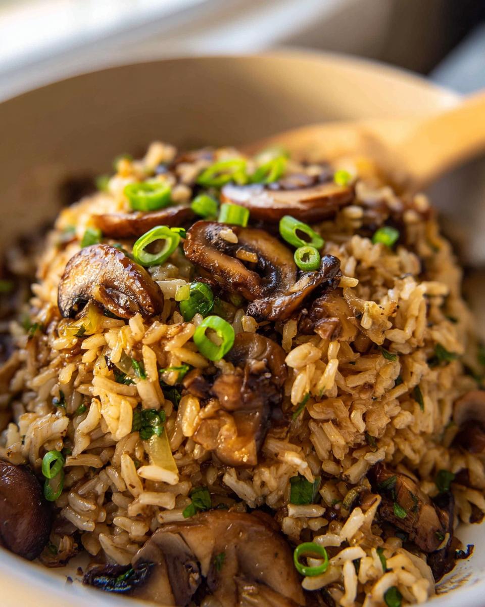 A close-up of a bowl filled with a flavorful Mushroom Rice Recipe, garnished with sautéed mushrooms and green onions.